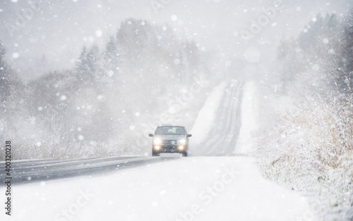 The car is driving on a winter road in a blizzard 
