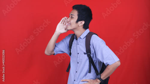 Obraz na plátne Young happy asian man announcing information with hands cup around mouth isolate