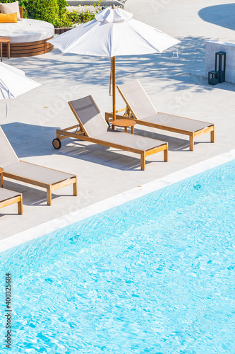 Umbrella and deck chair around outdoor swimming pool in hotel resort Fototapet
