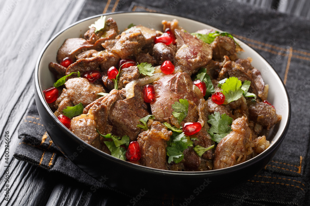 Fried chicken liver, hearts and gizzards with onions, walnuts and pomegranate close-up in a bowl on the table. horizontal Fried chicken liver, hearts and gizzards with onions, walnuts and pomegranate close-up in a bowl on the table. horizontal