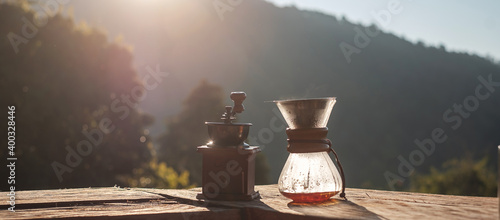 Hot arabica coffee and Vintage coffee drip equipment on wooden table in the morning with mountain and nature background photo