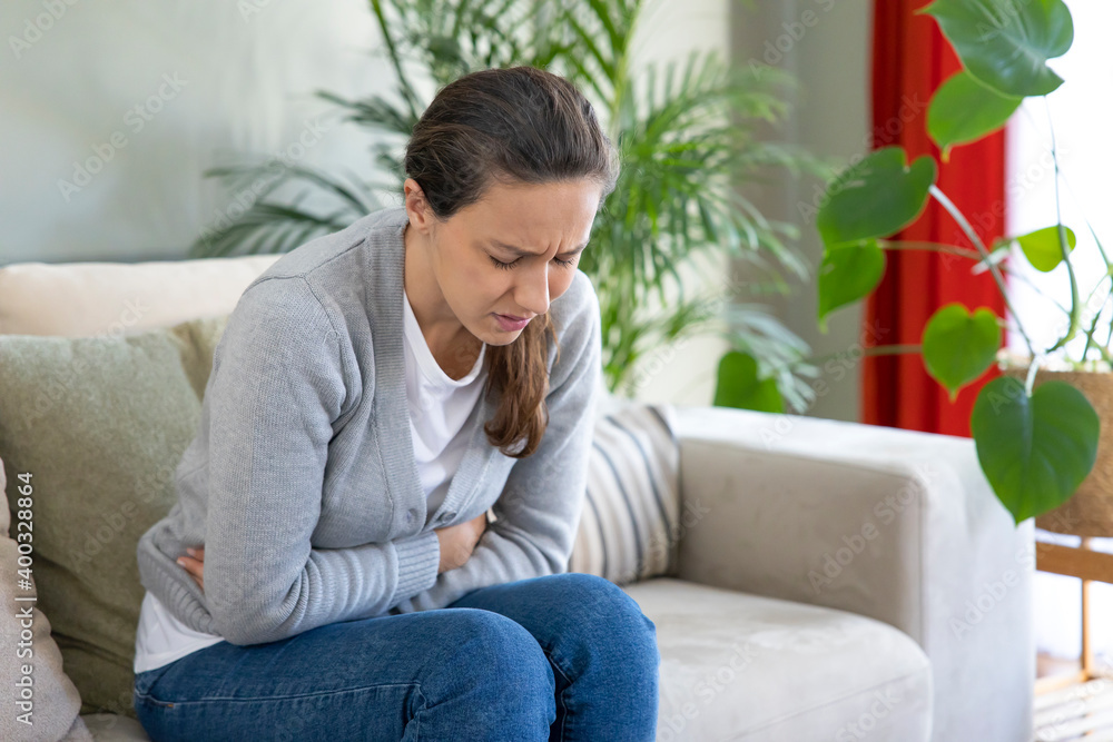 Young woman suffering PMS pain on sofa. Young woman suffering PMS pain on sofa.