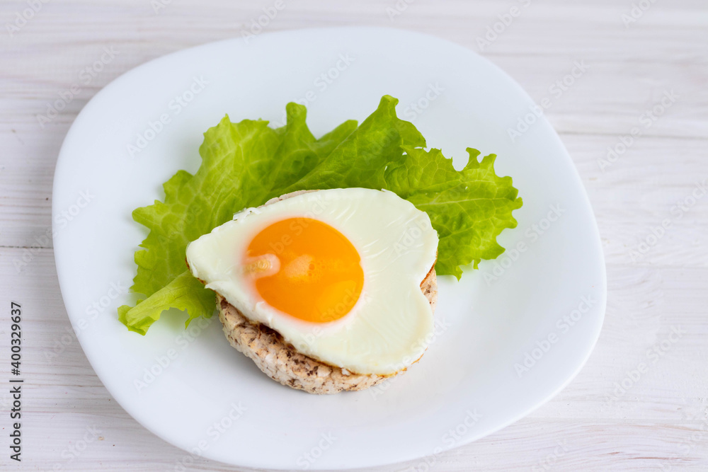 breakfast scrambled eggs in the form of a heart on bread and salad.concept of Valentine's day.on a white background breakfast scrambled eggs in the form of a heart on bread and salad.concept of Valentine's day.on a white background