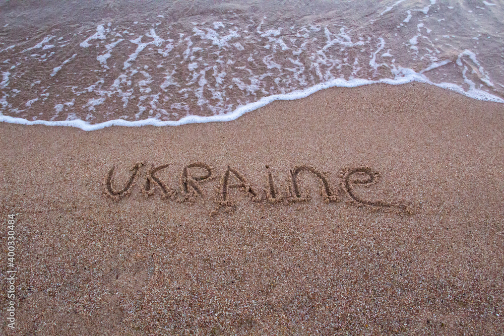 The beach with sea waves running on the sand and the word UKRAINE is drawn on the sand. Beautiful view on the waves The beach with sea waves running on the sand and the word UKRAINE is drawn on the sand. Beautiful view on the waves