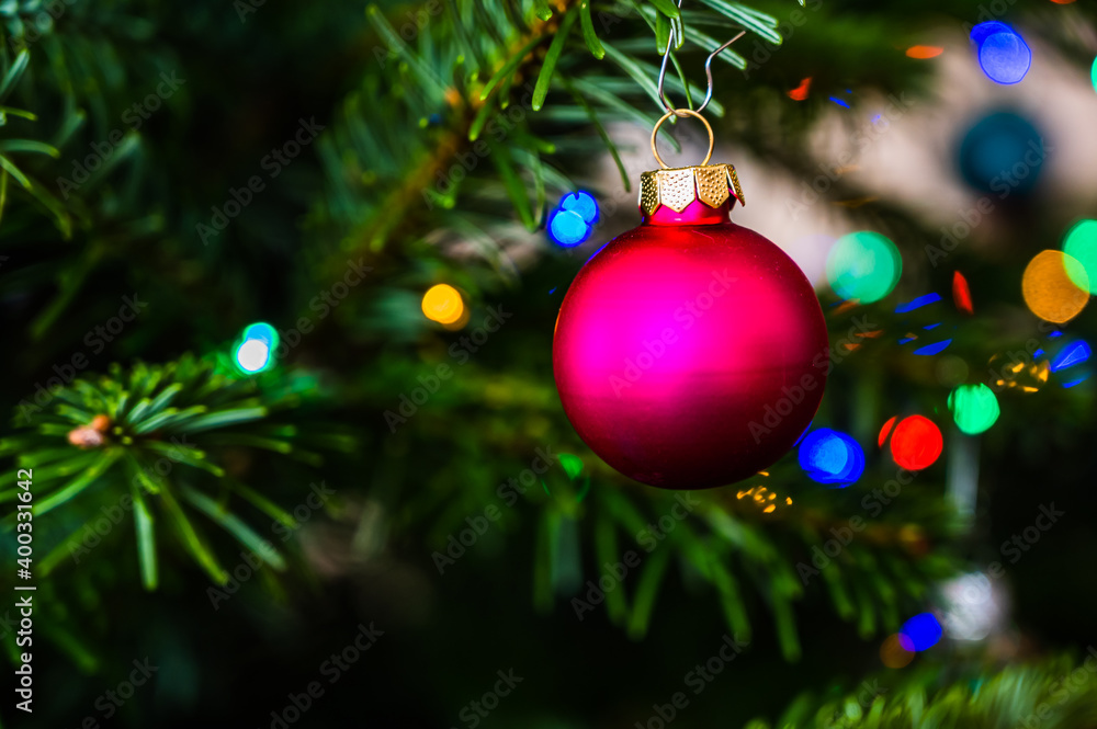 A closeup shot of a pink Christmas ball on a Christmas tree decorated with led lights