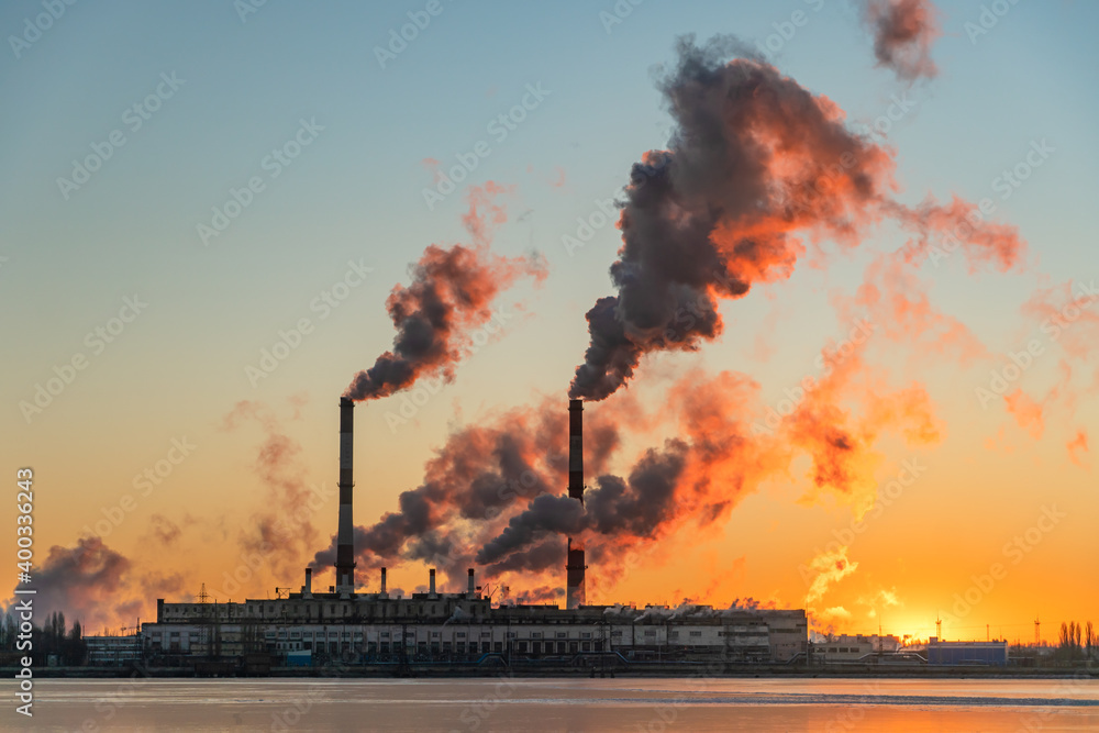 Pipes of an industrial enterprise. Emissions of smoke into the atmosphere and Pollution. Red sky at sunrise