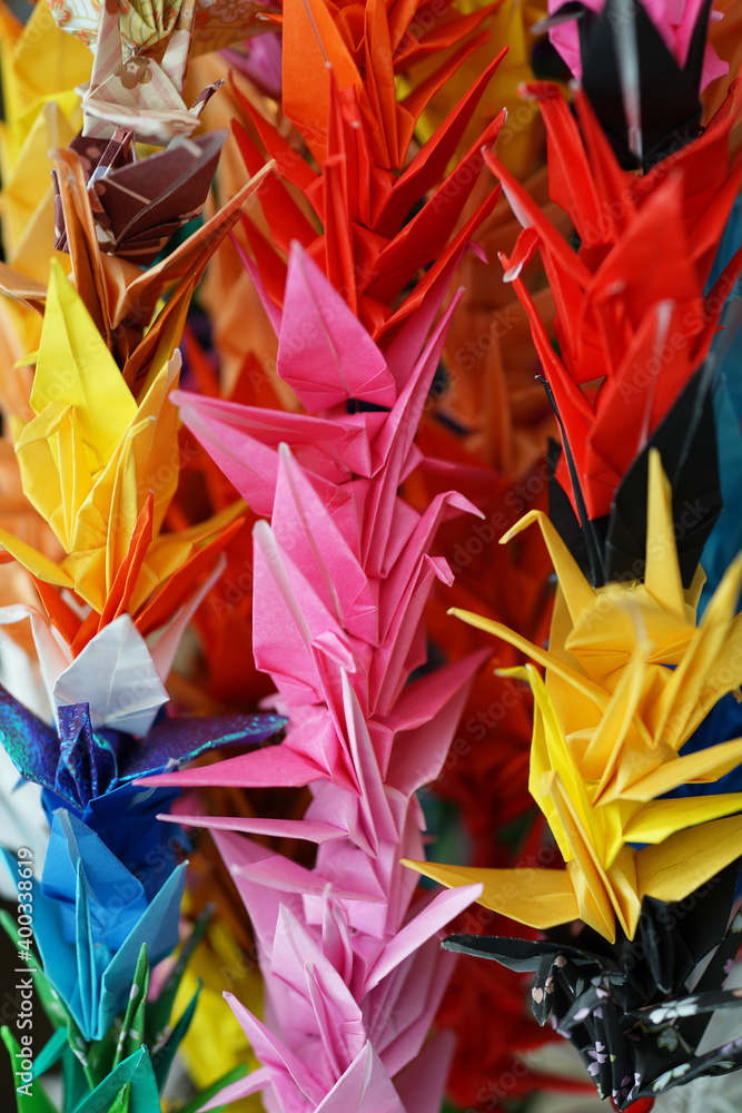 Origami multicolor paper birds decoration in a Japanese garden in nature, wedding origami cranes