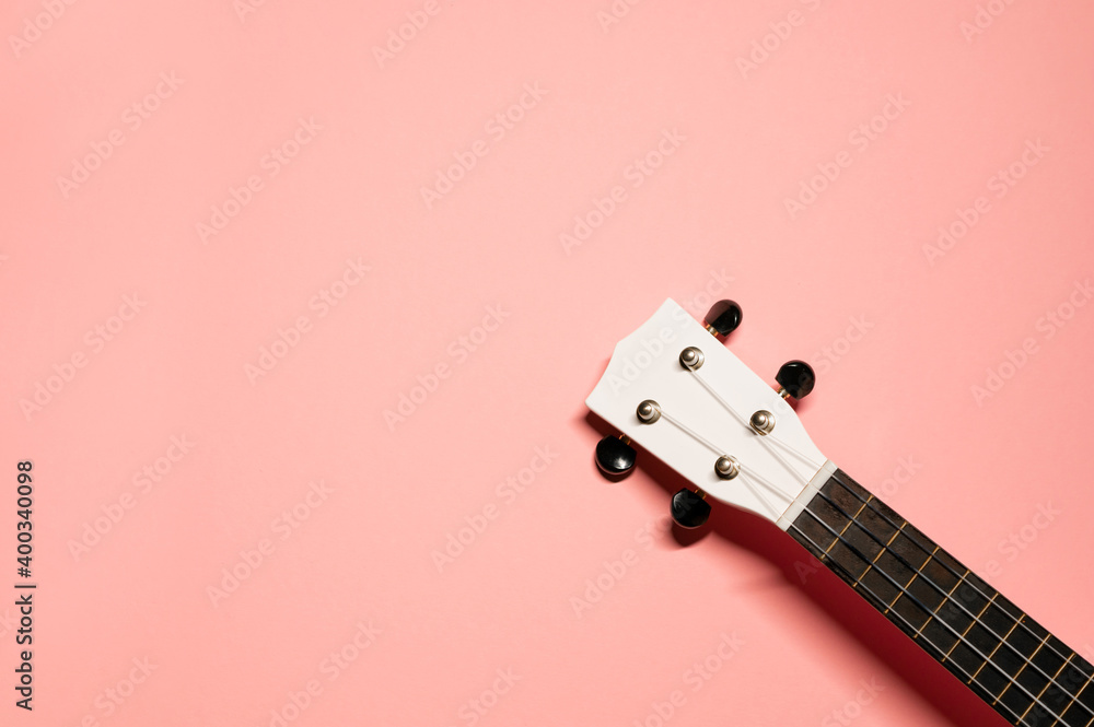 Ταπετσαρία Simple flat lay shot on a pastel pink background with a white and brown fretboard with nylon strings of hawaiian ukulele guitar