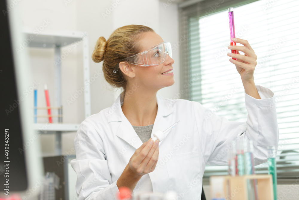 female technician looking at liquid in glass beaker female technician looking at liquid in glass beaker