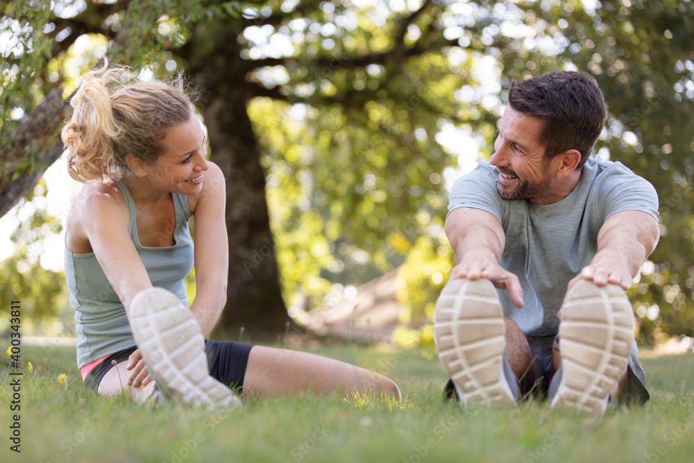 happy sporty couple stretching outdoors in park