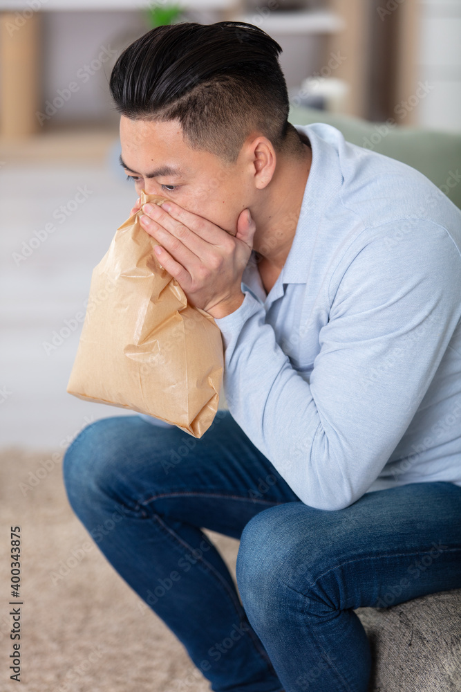 stressed asian man breathing with paper bag stressed asian man breathing with paper bag