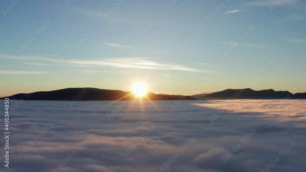 Dramatic sunrise in mountains with low clouds covering valley from aerial view. Trucking right drone shot. Dramatic sunrise in mountains with low clouds covering valley from aerial view. Trucking right drone shot.