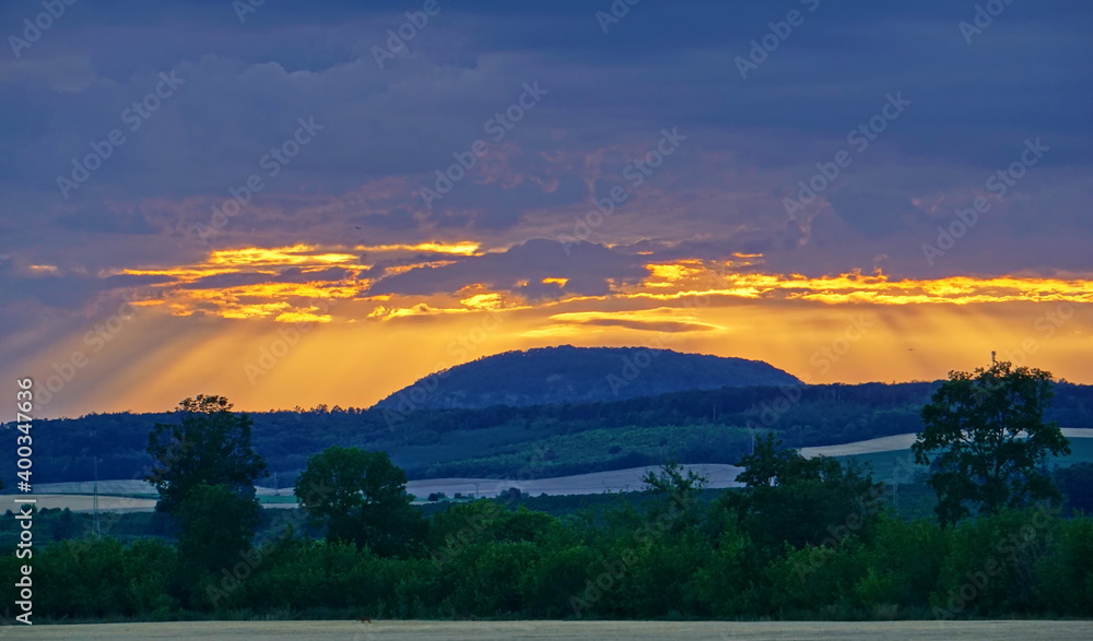 Obraz premium Hill under clouds illuminated by sun
