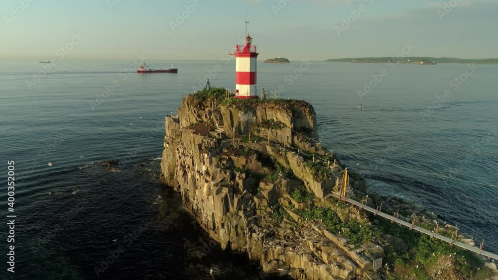 Drone orbit scenic old Basargin lighthouse beacon on sea island Vladivostok. Orange sunset. Emotional view, birds seagulls flock close up fly. Historical travel attraction. Emotional Russia film. 4k Drone orbit scenic old Basargin lighthouse beacon on sea island Vladivostok. Orange sunset. Emotional view, birds seagulls flock close up fly. Historical travel attraction. Emotional Russia film. 4k