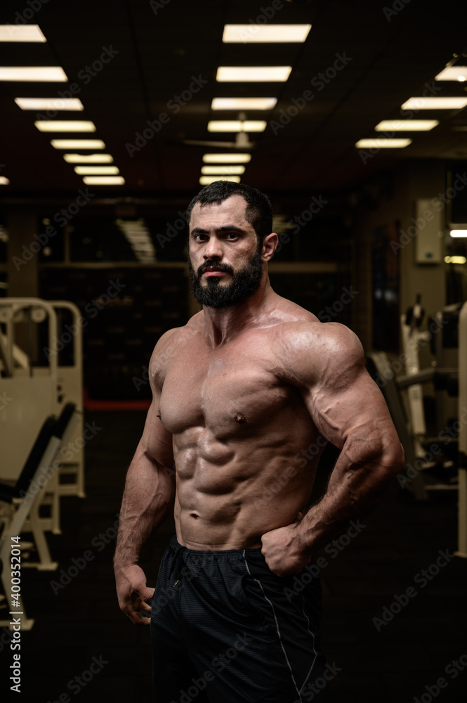 strong young bearded caucasian man with perfect sport physique body in dark fitness bodybuilding gym strong young bearded caucasian man with perfect sport physique body in dark fitness bodybuilding gym