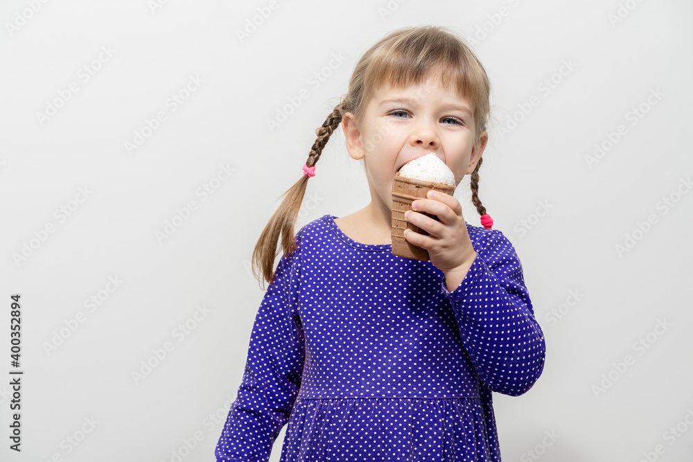 happy little caucasian girl in a blue dress eating ice cream. happy little caucasian girl in a blue dress eating ice cream.