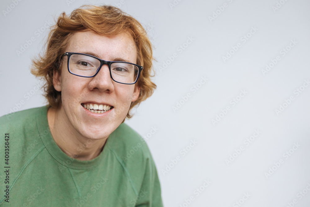 Fototapeta premium Red-haired man with glasses, smiling on a light background. copy space