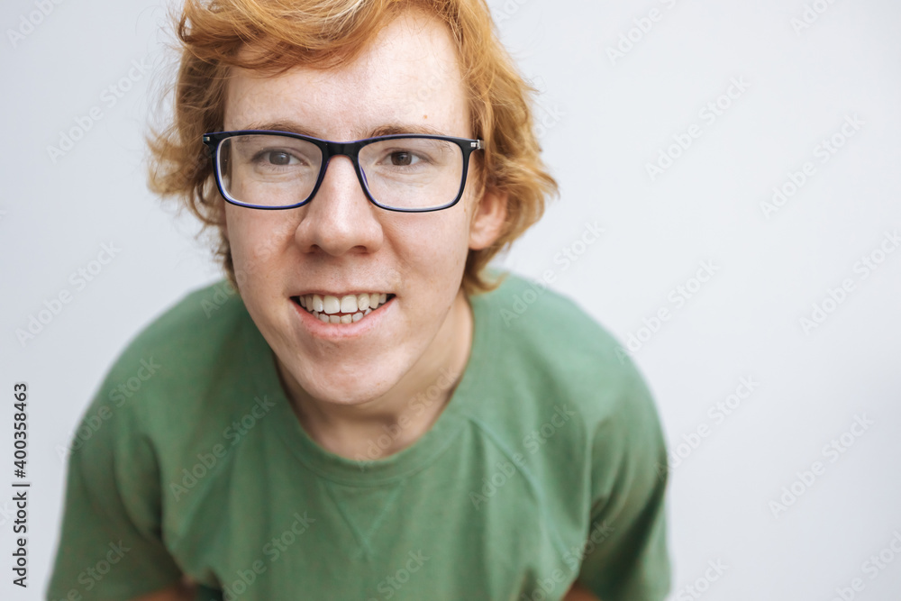 red-haired man in glasses and a green T-shirt looks at the camera and smiles on a white background red-haired man in glasses and a green T-shirt looks at the camera and smiles on a white background