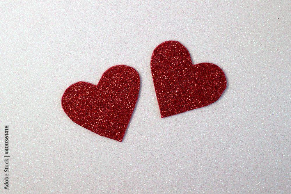 Hearts cut out of red glitter paper on a sparkly white background, close up Hearts cut out of red glitter paper on a sparkly white background, close up