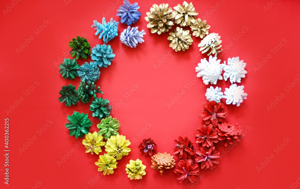 Christmas decoration of pinecones on a red background. Red, Yellow, Blue, green, white and golden cones.