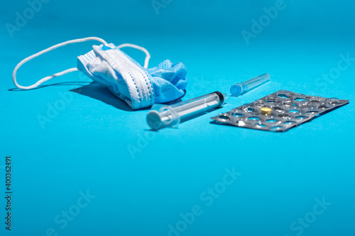 Blue face mask, pills, syringe on blue background. Medicine and healthcare. Medications and pharmacy. Low prespective.