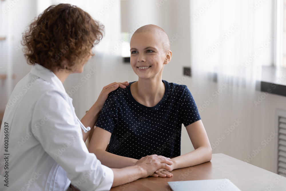 Hopeful young sick woman sit at desk in doctor office listen to attending physician believe trust her. Happy grateful female patient talk to oncologist at meeting feel cancer free excited of recovery Hopeful young sick woman sit at desk in doctor office listen to attending physician believe trust her. Happy grateful female patient talk to oncologist at meeting feel cancer free excited of recovery