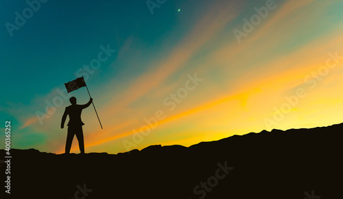 silhouette of businessman with flag on mountain top over sunset sky background, business, success, leadership and achievement concept © BNMK0819