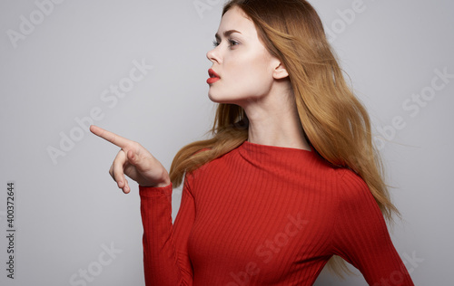 Portrait of a beautiful woman in a red shirt on a gray background gesturing with hands Copy Space