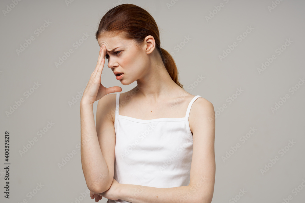 woman in white t-shirt holds hand near face health problems puzzled look migraine headache woman in white t-shirt holds hand near face health problems puzzled look migraine headache