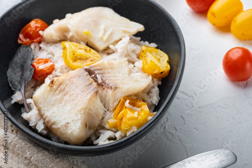 Tilapia fish with basmati rice and cherry tomatoes in bowl, on white background