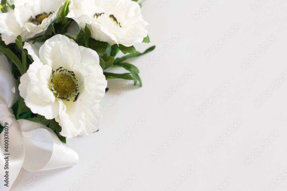 White flowers on a white background tied with a white satin ribbon White flowers on a white background tied with a white satin ribbon