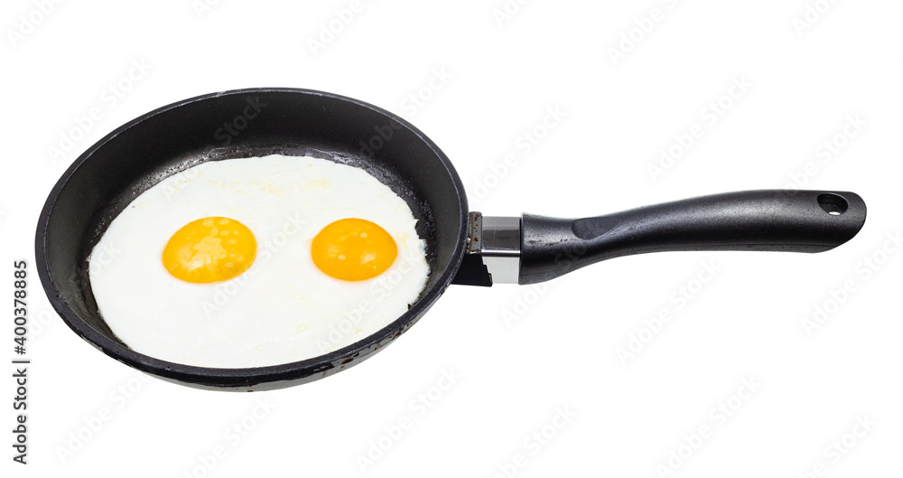 two fried eggs in black frying pan isolated on white background two fried eggs in black frying pan isolated on white background