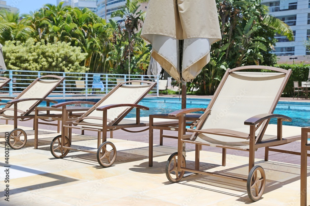 Near the pool, parasol and lounge chairs. At the background garden and buildings. Near the pool, parasol and lounge chairs. At the background garden and buildings.