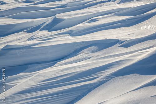 Snow texture. Wind sculpted patterns on snow surface. Wind in the tundra and in the mountains on the surface of the snow sculpts patterns and ridges (sastrugi). Arctic, Polar region. Winter background © Andrei Stepanov