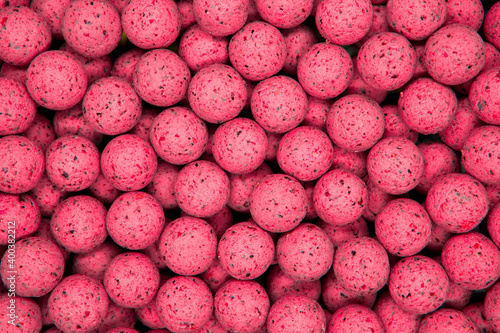 Small, sweet pink balls. Round boilies used as carp fishing bait. Abstract pink background photo