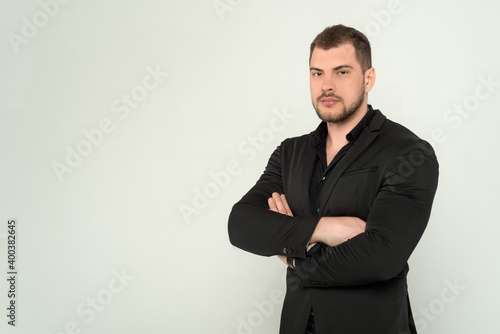 Close up of young business man in a suit with crossed arms on a white background