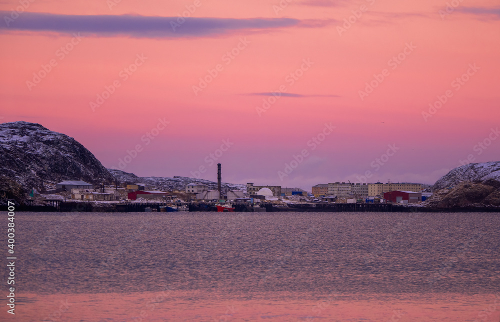 Magical colorful sunset in the Polar North. View of the winter city of Teriberka.