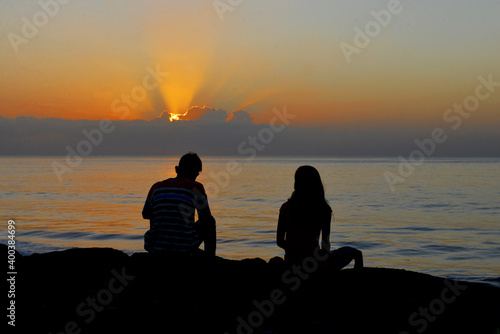 Silhouette of a couple enjoy sunrise at Matahari Beach in Bali Island, Indonesia. photo