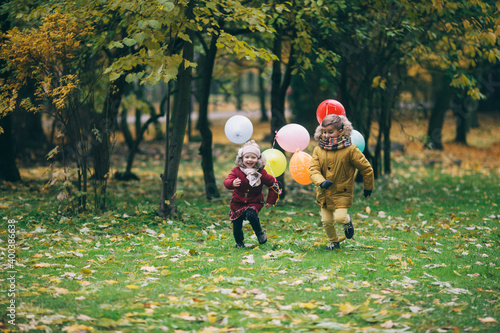 brother and sister running through an autumn park with balloons