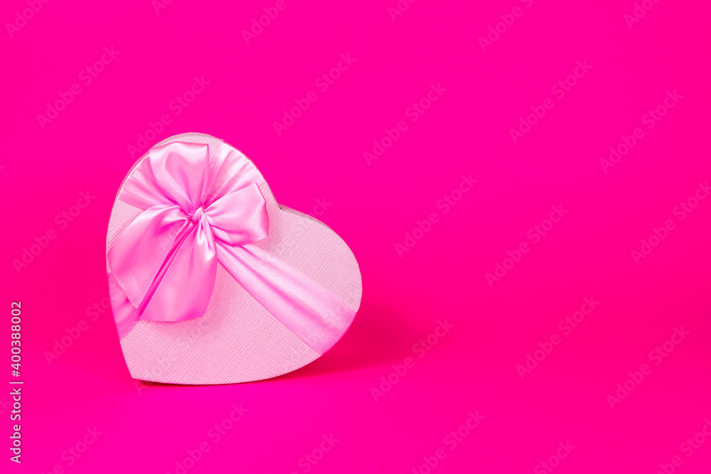 Valentine's Day holiday. Pink heart box with bow on pink background. Gift heart. Love and passion concept. Valentine's Day gift.