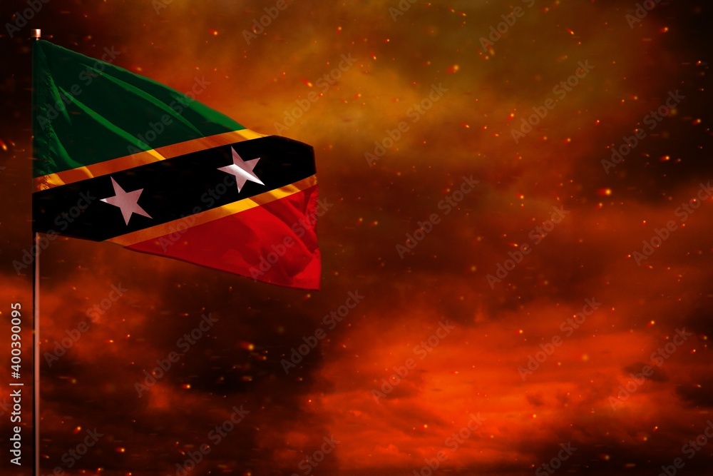 Fluttering Saint Kitts and Nevis flag mockup with blank space for your text on crimson red sky with smoke pillars background. Troubles concept. Fluttering Saint Kitts and Nevis flag mockup with blank space for your text on crimson red sky with smoke pillars background. Troubles concept.