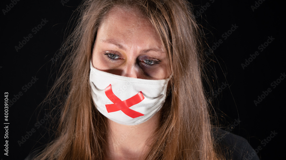 Battered woman, black eye, white mask with a red adhesive tape cross, symbol of forced silence. S.O.S Message
Battered woman, black eye, white mask with a red adhesive tape cross, symbol of forced silence. S.O.S Message