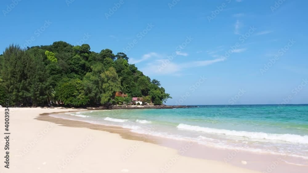 seacoast landscape background in sunny summer daylight shine on seawater, white foam waves lapping on the sandy shore, lush green island with clear blue sky and wispy clouds at back. relaxing place. seacoast landscape background in sunny summer daylight shine on seawater, white foam waves lapping on the sandy shore, lush green island with clear blue sky and wispy clouds at back. relaxing place.