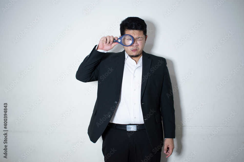 Young businessman looking at document through magnifying glass in white background
Young businessman looking at document through magnifying glass in white background
