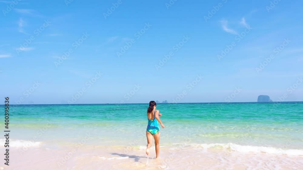 Beautiful white beach and blue clear sky in sunny day. A girl in swimming suit and relaxing in sea water in summer season in southern Thailand ocean. Travel to Phuket beach with happiness. Beautiful white beach and blue clear sky in sunny day. A girl in swimming suit and relaxing in sea water in summer season in southern Thailand ocean. Travel to Phuket beach with happiness.