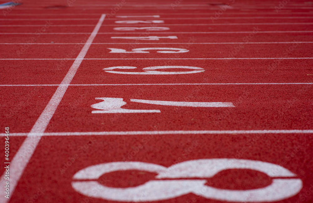 White numbers on starting line of a running track field, 1-8, with straight white lines divided each track equally.