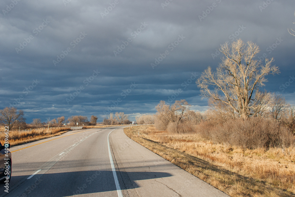 Beautiful dark blue sky over the highway. A landscape with a very unusual sky, trees without leaves and an asphalt road on an autumn day before a thunderstorm. Pacific Junction, IA, USA, 11-30-2019 Beautiful dark blue sky over the highway. A landscape with a very unusual sky, trees without leaves and an asphalt road on an autumn day before a thunderstorm. Pacific Junction, IA, USA, 11-30-2019