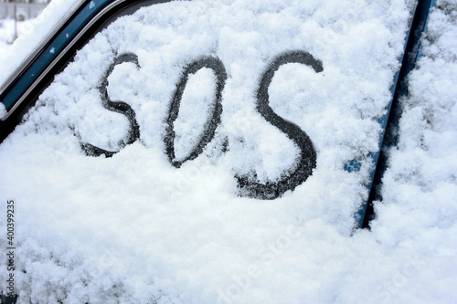 A handwritten SOS message is written on the car door window.