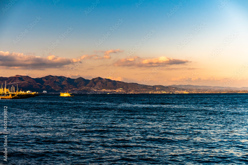 sunset over the coastal harbor with mountains as the background in Beppu oita