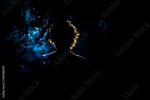 Colored silhouette of a smoking man on dark background.